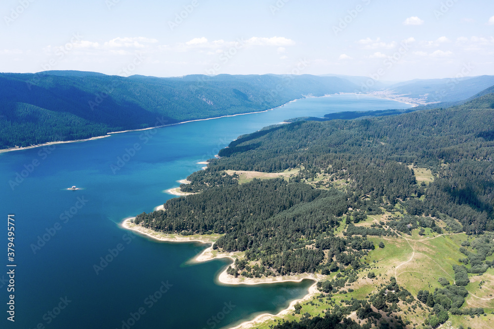Beautiful authentic landscape, aerial view from drone. Coniferous forests on banks of Batak reservoir located in Rhodope Mountains, Bulgaria. Attracts many tourists, fishermen and hunters. Travel 