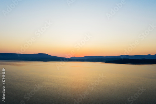Beautiful authentic landscape of rising sun over lake  silhouettes of mountains  aerial view from the drone. Batak reservoir located in Rhodope Mountains  Bulgaria. Attracts many tourists. Travel 
