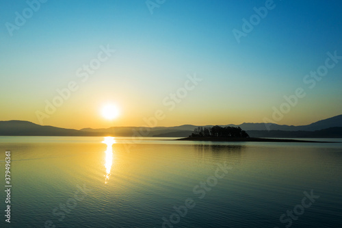 Beautiful authentic landscape of rising sun over lake  silhouettes of mountains  aerial view from drone. Batak reservoir located in Rhodope Mountains  Bulgaria. Attracts many tourists. Travel 
