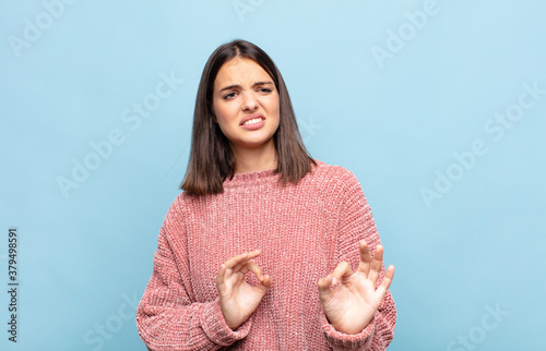 young pretty woman feeling disgusted and nauseous, backing away from something nasty, smelly or stinky, saying yuck