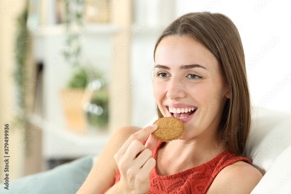 Happy woman is eating cereal cookie at home Happy woman is eating cereal cookie at home
