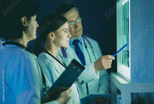 Group of doctors examining x-rays in a clinic, thinking of a diagnosis photo