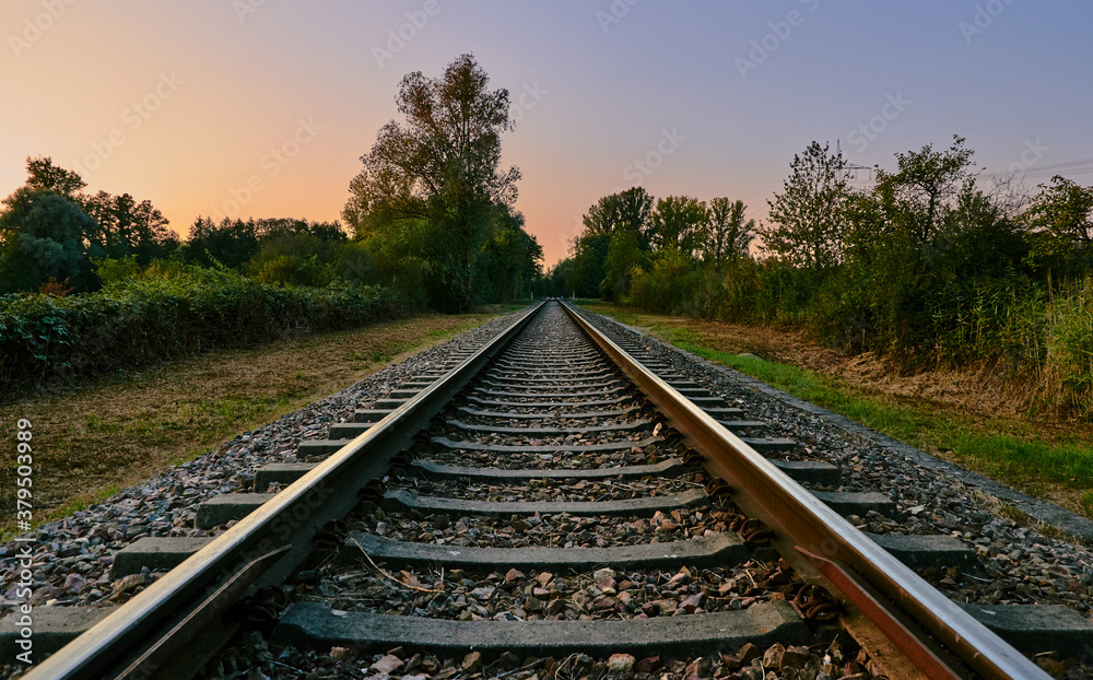 Rail track in landscape with colorful sky and sunset on a beautiful summer evening 
