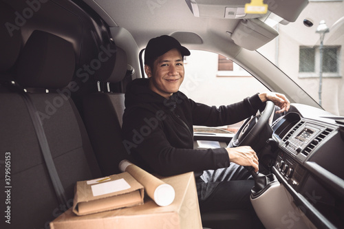 Portrait of smiling driver with package sitting in truck photo