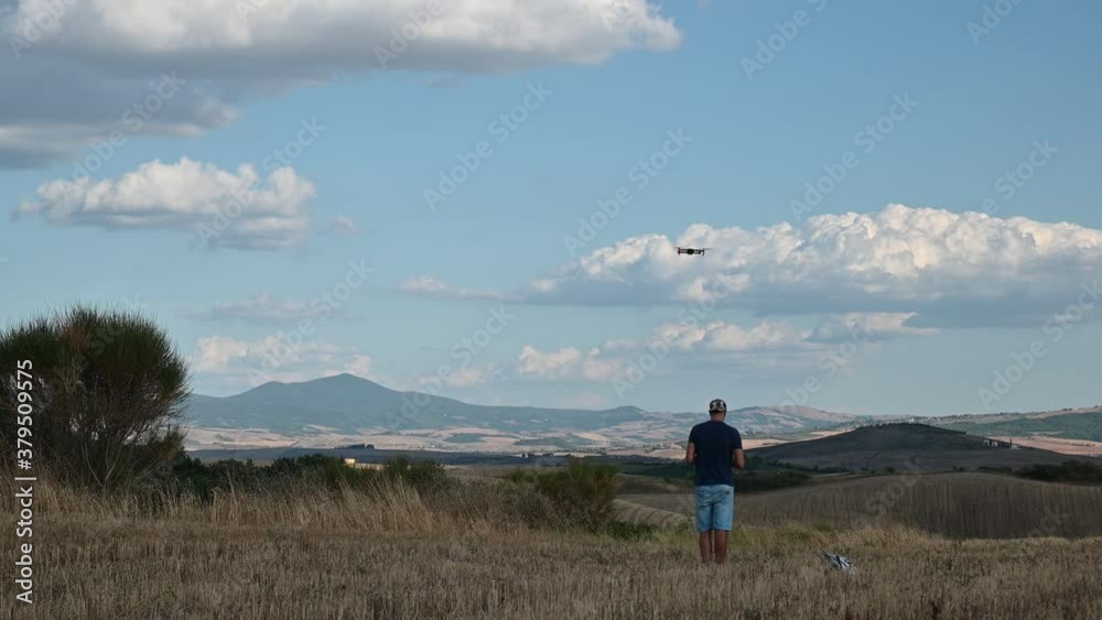 Val d'Orcia, Siena, Tuscany, Italy. August 2020. A man pilots his drone in the amazing landscape of the Tuscan countryside. Nice sunny day. Val d'Orcia, Siena, Tuscany, Italy. August 2020. A man pilots his drone in the amazing landscape of the Tuscan countryside. Nice sunny day.
