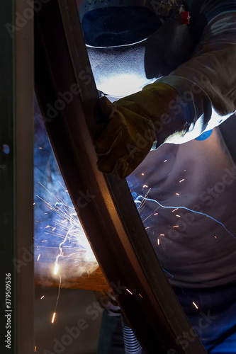 The welder is welding to structure steel material with gas metal arc welding process in the workshop. © Funtay