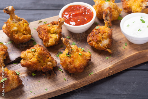Chicken wings nuggets with sauces on wooden background .