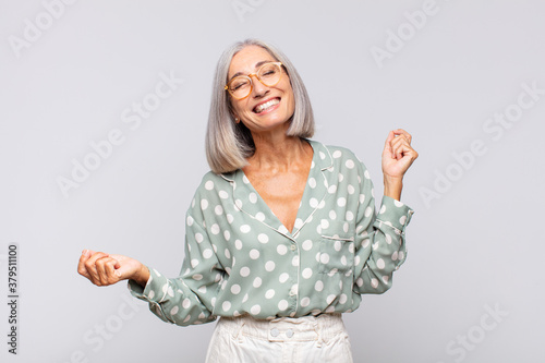 Wallpaper Mural gray haired woman smiling, feeling carefree, relaxed and happy, dancing and listening to music, having fun at a party Torontodigital.ca