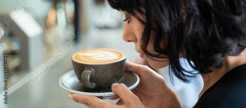Konstfotografi Beautiful customer in cafe restaurant holding cup of latte art coffee
