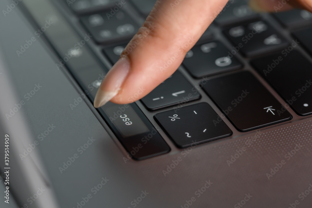 close-up female hand pressing esc button on laptop keyboard close-up female hand pressing esc button on laptop keyboard