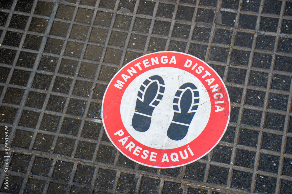 Footprint sign for stand at a distance, in the street of Buenos Aires, Argentina. Social distance word tag poster. Instruction against propagation. New normal. Social distancing during covid19