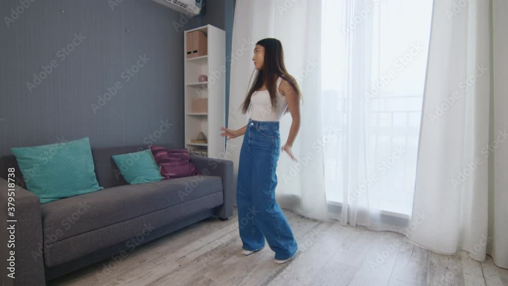 Energetic dancing of a happy girl. Pretty young woman dancing in living room and listening music. Energetic dancing of a happy girl. Pretty young woman dancing in living room and listening music.