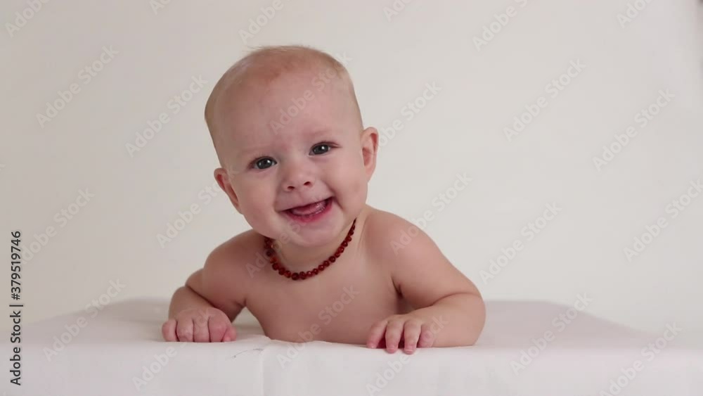 Happy Caucasian baby boy drooling on white blanket Happy Caucasian baby boy drooling on white blanket