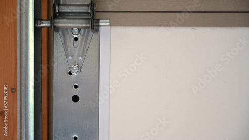 Side guide of garage door being opened in slow motion.  No sound.  