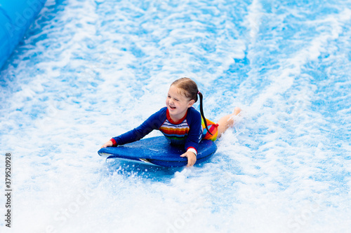 Photography Little girl surfing in beach wave simulator