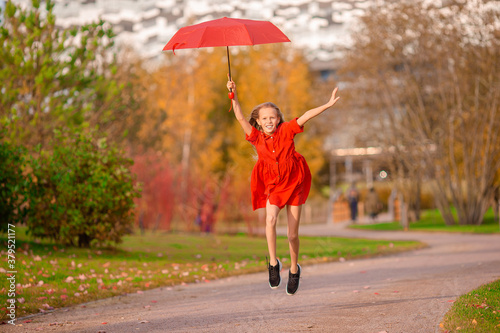 Happy child girl laughs under red umbrella