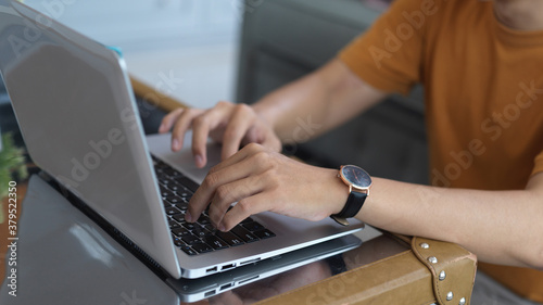 Hands typing on laptop keyboard on coffee table in living room