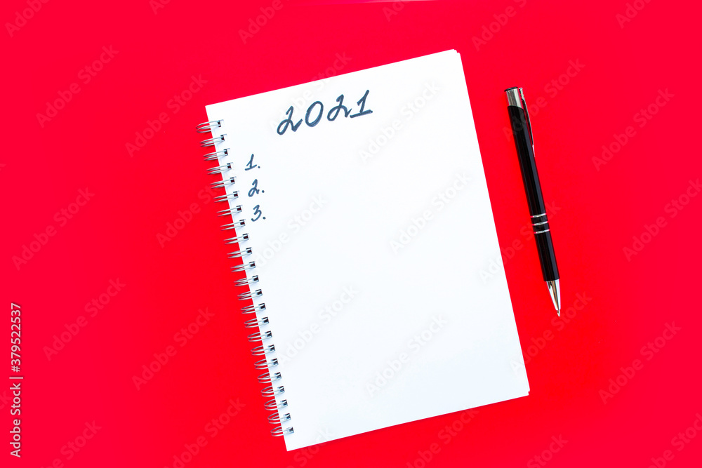 The inscription 2021. Planning list and numbers 1, 2 and 3. Notebook with a spiral and black pen on a red background. New Year and Christmas concept. The inscription 2021. Planning list and numbers 1, 2 and 3. Notebook with a spiral and black pen on a red background. New Year and Christmas concept.