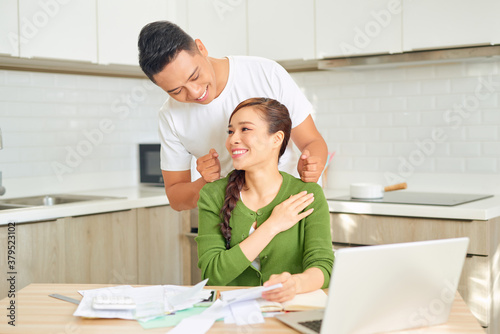 Guy is doing massage his girlfriend while she is working with a laptop
