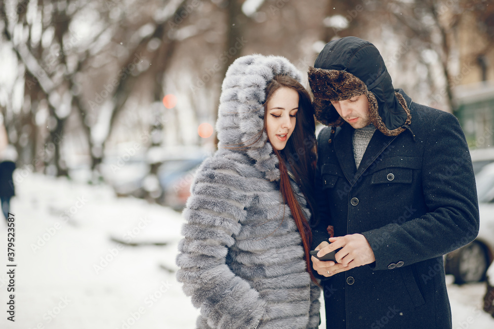 Cute couple walking in a winter city. Elegant woman in a gray fur coat