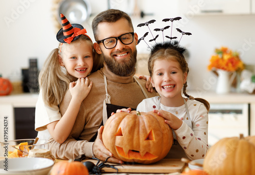 happy family father and children prepare for Halloween by carving pumpkins at home in kitchen.