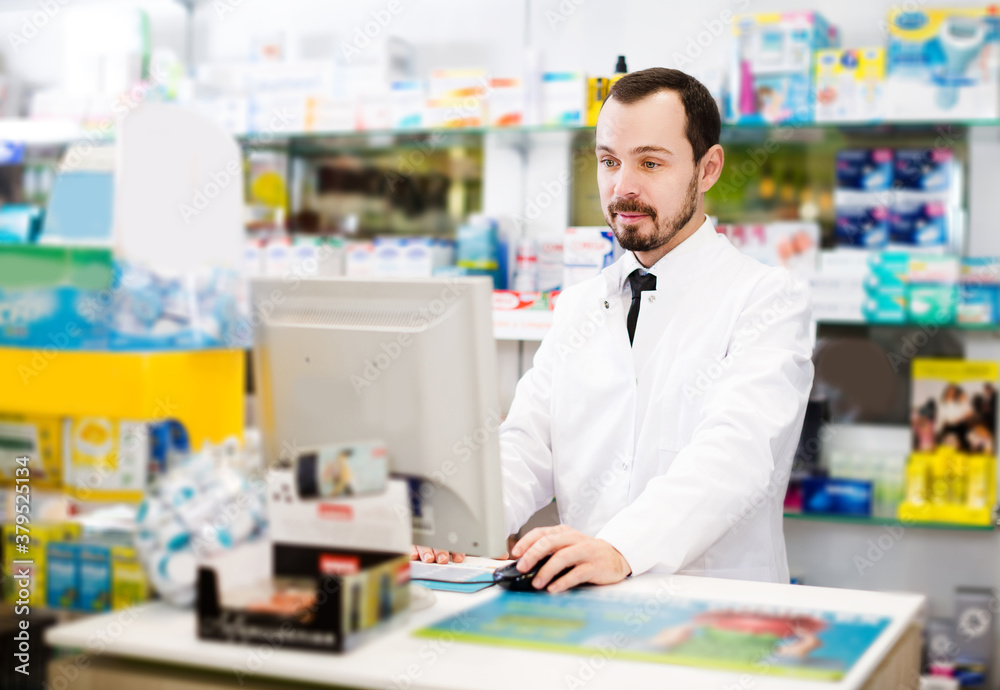 Smiling man pharmacist writing down assortment of drugs in pharmacy