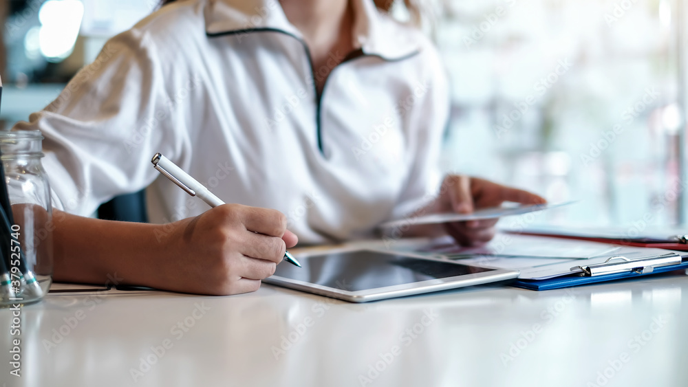 Close up. Image of woman working with tablet in office.