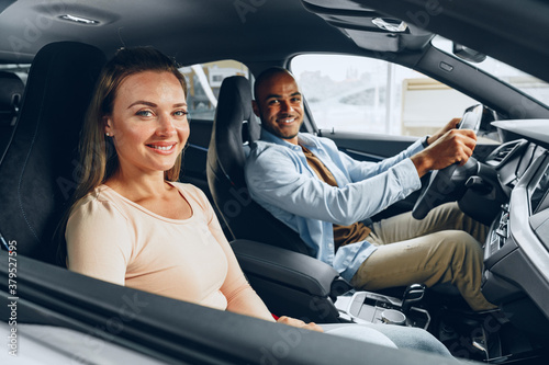Joyful young couple looking around inside a new car they are going to buy in a car shop © fotofabrika