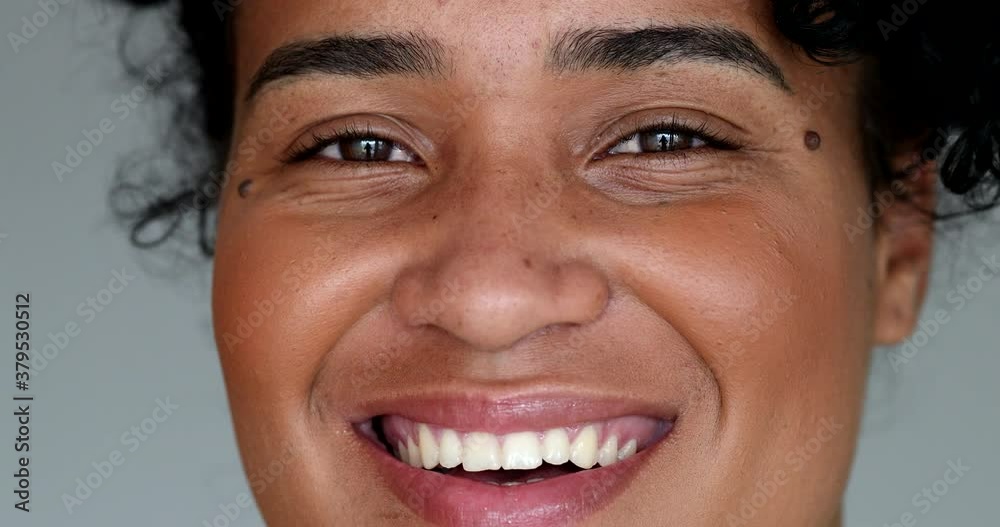 Young black woman macro close-up face looking at camera smiling Young black woman macro close-up face looking at camera smiling