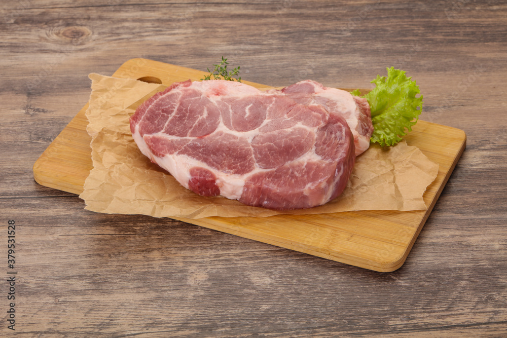 Raw pork steak over wooden board Raw pork steak over wooden board