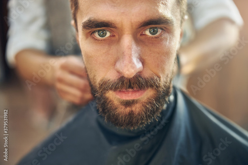 Reserved barbershop visitor getting covered with a barber cape