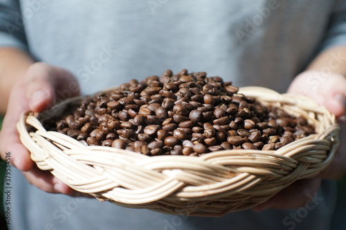 Man holds in hands wattled basket with roasted coffee beans