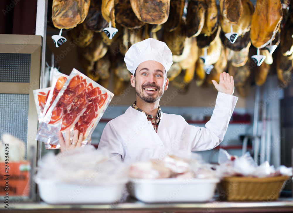 Male shop assistant demonstrating sliced bacon in butcher shop