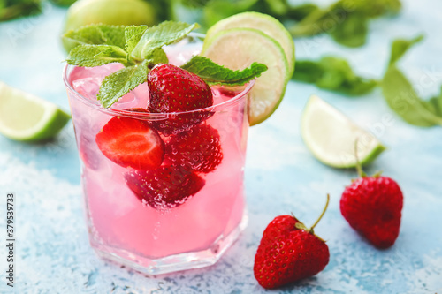 Glass of fresh strawberry mojito on color background