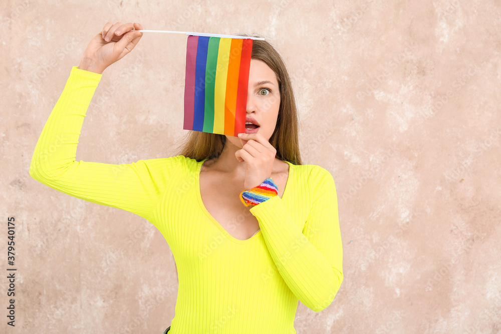 Surprised young woman with LGBT flag on color background Surprised young woman with LGBT flag on color background