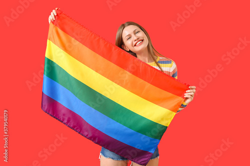 Young woman with LGBT flag on color background