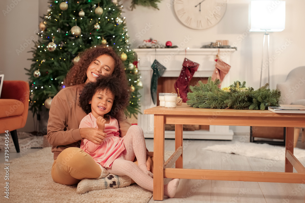 Cute African-American girl and her mother at home on Christmas eve Cute African-American girl and her mother at home on Christmas eve