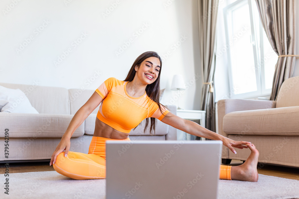 Girl training at home, doing workout and watching videos on laptop, training in living room. Beautiful woman is doing side plank exercise. She is watching video on the internet and repeating the tasks Girl training at home, doing workout and watching videos on laptop, training in living room. Beautiful woman is doing side plank exercise. She is watching video on the internet and repeating the tasks
