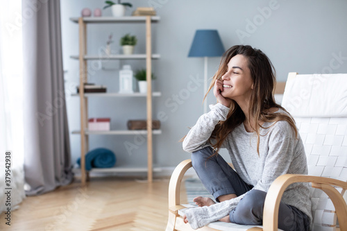Young millennial woman enjoying morning in cozy chair at home.