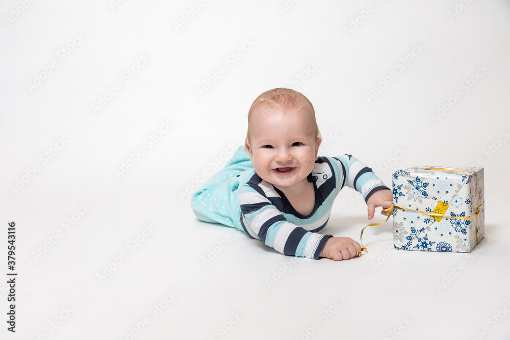Smiling toddler boy is holding Christmas package lying on the floor Smiling toddler boy is holding Christmas package lying on the floor