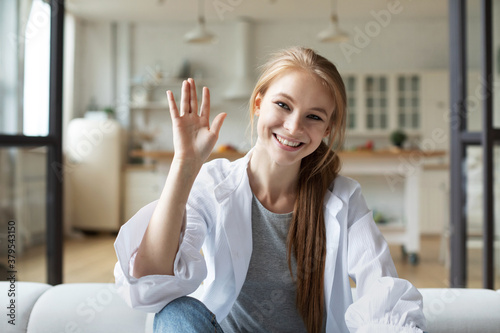 Smiling young woman influencer waving looking at camera talking making video chat, webcam view.