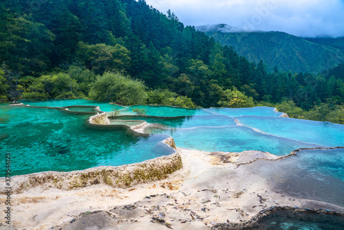 The turquoise color hot spring pools in Huanglong Valley, Sichuan, China, on summer time. photo