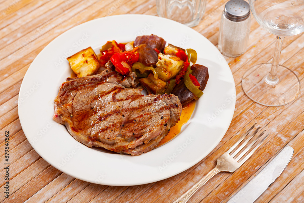 Delicious roasted veal steak with sauteed bell pepper, aubergine and onion