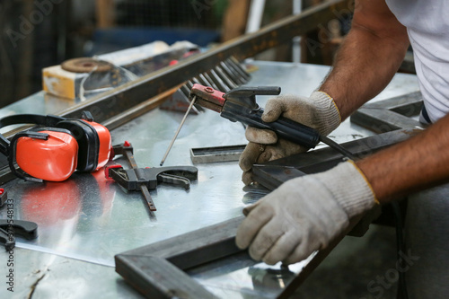 worker welds metal with electric welding