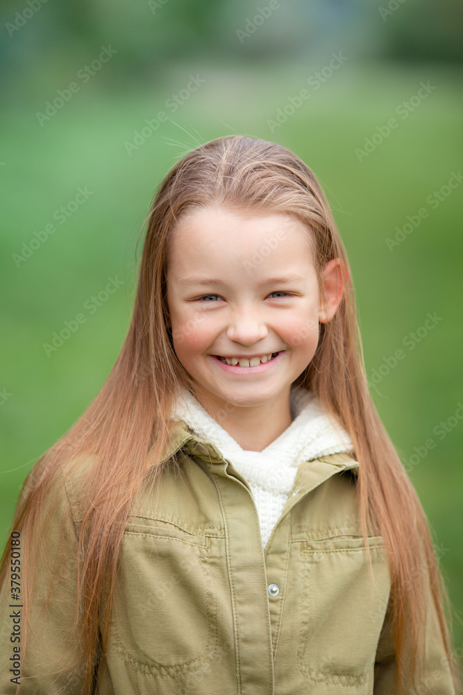 Long-haired girl in an autumn green coat on a background of plants Long-haired girl in an autumn green coat on a background of plants