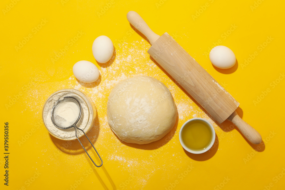 Fototapeta premium Concept for baking with dough on yellow background