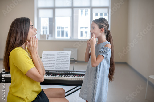 Photography Girl in blue dress and her teacher doing voice exercises