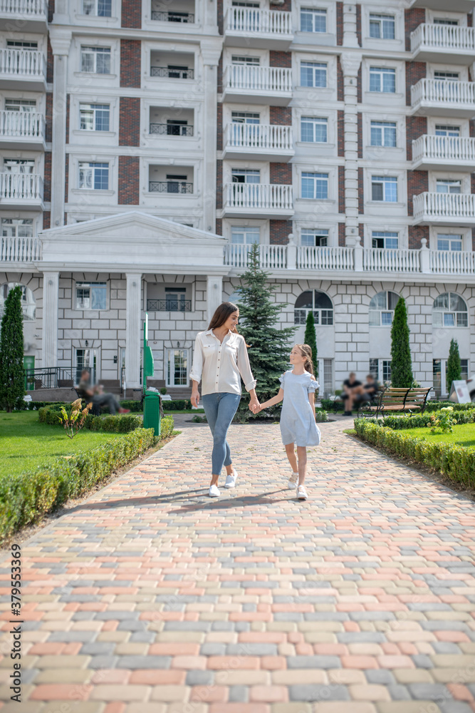 Mom and daughter walking and holding hands Mom and daughter walking and holding hands