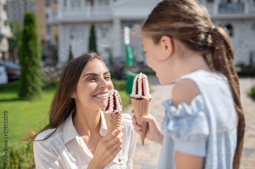 Mom and daughter eating ice-cream and looking enjoyed