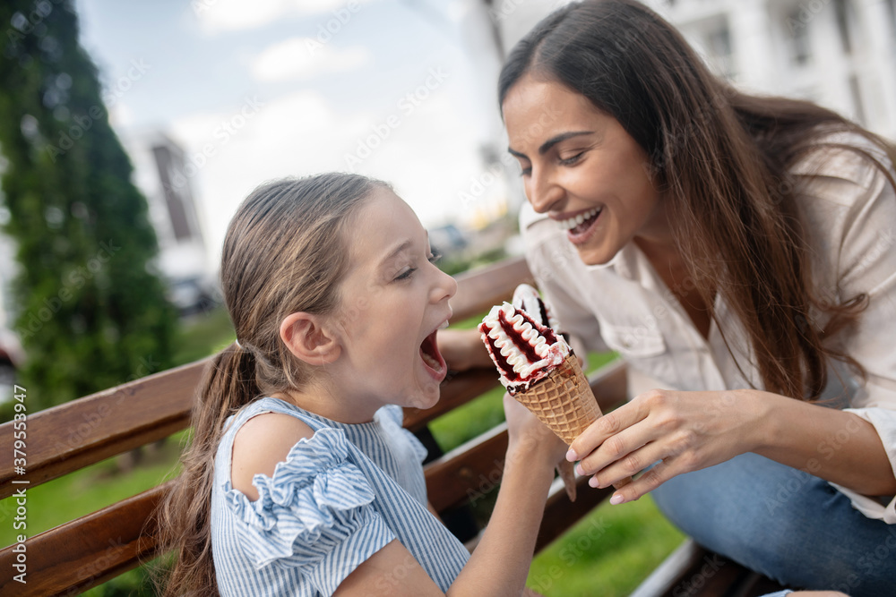 Mom and daughter eating ice-cream and having fun Mom and daughter eating ice-cream and having fun
